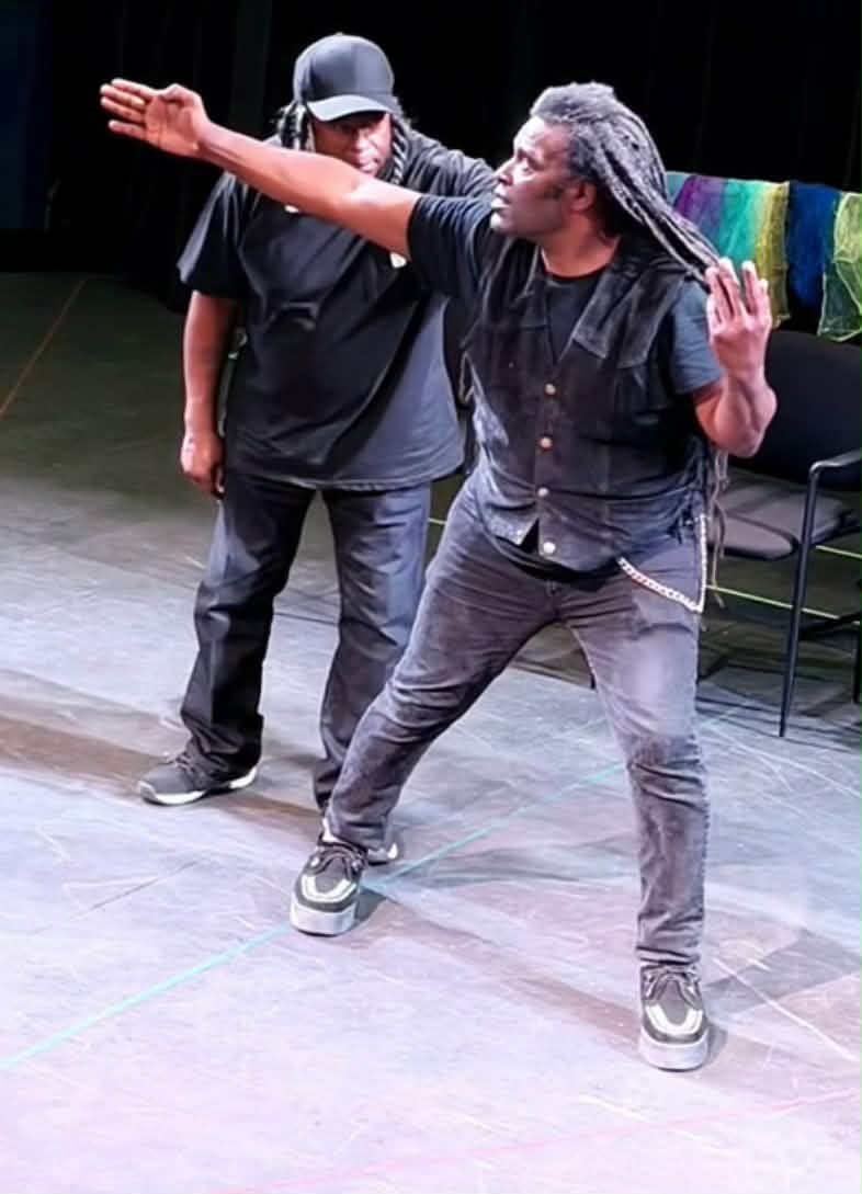 Two performers in dynamic action poses on stage